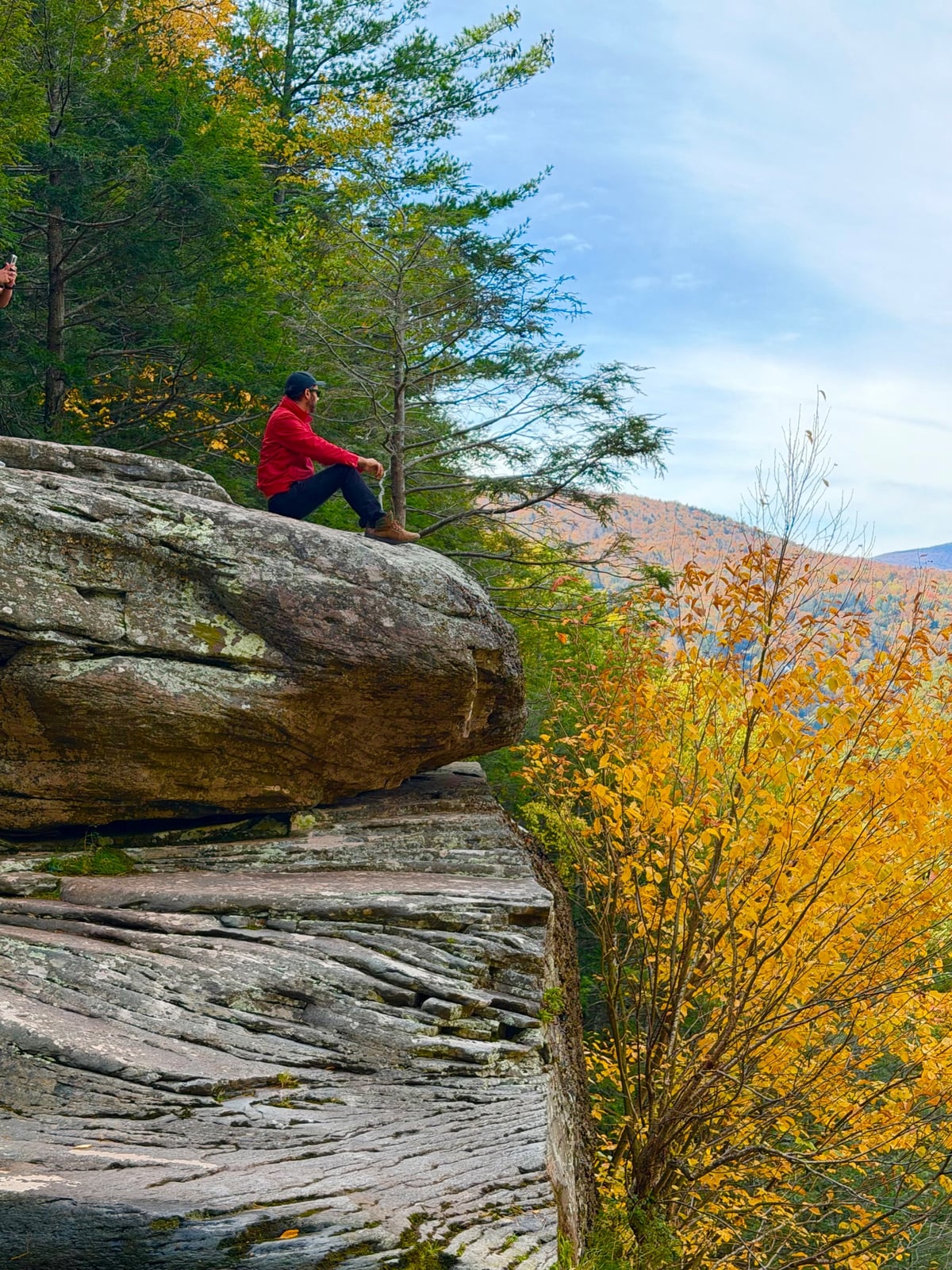 Sitting on a large rock overlooking autumn trees near Kaaterskill Falls