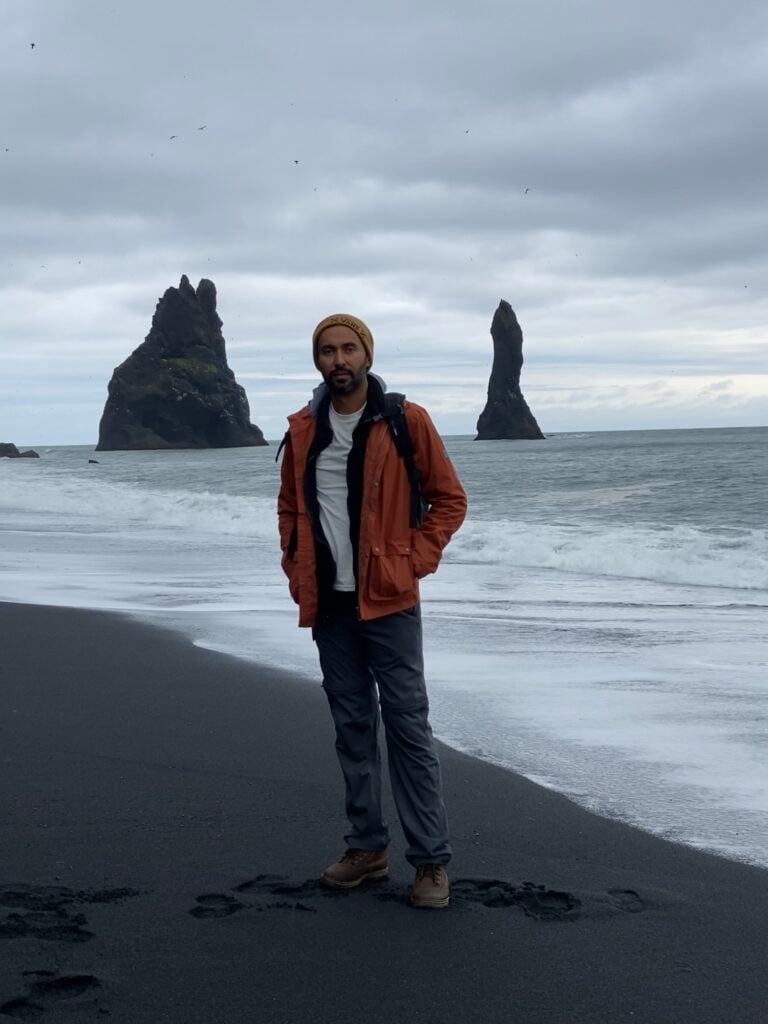 Standing on Reynisfjara black sand beach with the Reynisdrangar sea stacks behind